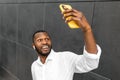 Portrait of young afro american male taking selfies with his mobile phone isolated on grey background outdoors. Handsome Royalty Free Stock Photo