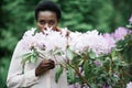 Portrait of young afro american woman surrounded purple flowers in park Royalty Free Stock Photo