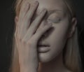 Young albino woman with closed eyes touches her face.
