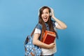 Portrait of young amazed excited woman student in denim clothes with backpack headphones listening music, holding school Royalty Free Stock Photo