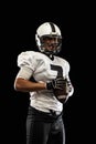 Portrait young American football player, athlete in black white sports uniform posing  on dark studio background Royalty Free Stock Photo