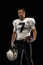 Portrait young American football player, athlete in black white sports uniform posing  on dark studio background Royalty Free Stock Photo