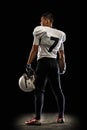 Portrait young American football player, athlete in black white sports uniform posing isolated on dark studio background Royalty Free Stock Photo