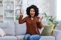 Portrait of a young angry African American woman sitting on the sofa at home, screaming and gesturing emotionally with Royalty Free Stock Photo