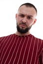 Portrait of young angry handsome bearded man with short dark hair wearing red striped sweatshirt, looking at camera Royalty Free Stock Photo