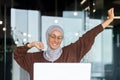 Portrait of young Arab businesswoman in hijab and glasses sitting in office at table with laptop. She is tired, has Royalty Free Stock Photo