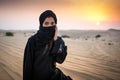 Portrait of a young Arab woman wearing traditional black clothing during beautiful sunset over the desert Royalty Free Stock Photo