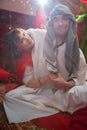 Portrait of young arabian muslim couple in traditional clothes in cozy red room. Fhoto shoot in easten style with male