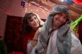 Portrait of young arabian muslim couple in traditional clothes in cozy red room. Fhoto shoot in easten style with male