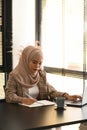 Portrait of young Arabic business woman wearing hijab is taking notes in notebook. Royalty Free Stock Photo