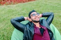 Portrait of Young Arabic Male Man, Student Lies on Chair, Smiling, Looking at Sky, Meditate on Background of Green Grass Royalty Free Stock Photo