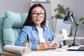 Portrait of a young Asian architect-designer woman in glasses works on a project,holds a tablet Royalty Free Stock Photo