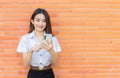 Portrait young Asian beautiful and pretty Thai girl student in uniform while using smartphone she happy confident smile and Royalty Free Stock Photo