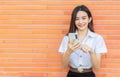 Portrait young Asian beautiful and pretty Thai girl student in uniform while using smartphone she happy confident smile and Royalty Free Stock Photo