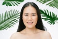 Portrait of young Asian beautiful woman healthy with skin natural makeup and clean fresh skin looking at camera in tropical leaves
