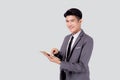 Portrait young asian business man in suit standing using tablet computer to internet isolated on white background. Royalty Free Stock Photo