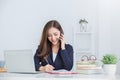 Portrait of young asian business woman talk on smartphone write in notebook with laptop in office. Royalty Free Stock Photo