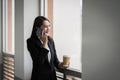 Portrait of a young Asian business woman talking over cellphone and holding cup of coffee in business building. Photo of beautiful Royalty Free Stock Photo