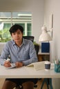 Young asian businessman sitting at home office and looking at camera. Royalty Free Stock Photo