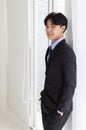 Portrait of young asian businessman who smart and handsome wearing black suit standing look at camera while smiling with look feel Royalty Free Stock Photo