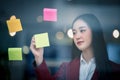 Portrait of Young asian businesswoman writing sticky paper pad on glass in modern office. Business plan concept Royalty Free Stock Photo