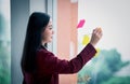 Portrait of Young asian businesswoman writing sticky paper pad on glass in modern office. Business plan concept Royalty Free Stock Photo