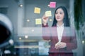 Portrait of Young asian businesswoman writing sticky paper pad on glass in modern office. Business plan concept Royalty Free Stock Photo