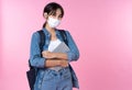 Portrait of young Asian college student wears face mask with laptop and backpack  over pink background. Royalty Free Stock Photo