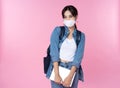 Portrait of young Asian college student wears face mask with laptop and backpack  over pink background. Royalty Free Stock Photo