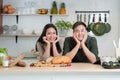 Portrait of young Asian couple smiling, placing hands on chin, looking at camera in the kitchen, happy wife and handsome husband Royalty Free Stock Photo