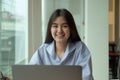 Portrait young asian girl looking camera while using laptop computer Royalty Free Stock Photo