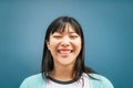 Portrait of young Asian girl smiling at camera - Happy Chinese woman having fun posing against blue background Royalty Free Stock Photo