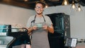 Portrait young Asian guy barista waitress holding coffee cup feeling happy at urban cafe. Asia small business owner boy in apron Royalty Free Stock Photo