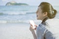 Portrait of young asian happy woman using smart phone at beach.technology concept.blurred beach sea background.clipping path Royalty Free Stock Photo