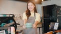 Portrait young Asian lady barista waitress holding coffee cup feeling happy at urban cafe. Asia small business owner girl in apron