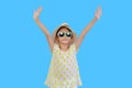Portrait of young asian little child girl wearing sunglasses and straw hat with open wide arms isolated on light blue background Royalty Free Stock Photo