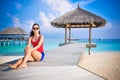 Portrait of young asian looking woman sitting near hut at beautiful tropical beach at Maldives Royalty Free Stock Photo