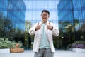 Portrait of young asian male designer, freelancer, businessman standing outside near office center. He stands Royalty Free Stock Photo