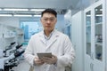 Portrait of a young Asian male scientist standing in a laboratory wearing protective glasses and gloves. He was holding Royalty Free Stock Photo