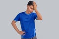 Portrait of a young Asian man with a blue t-shirt isolated on gray background, suffering from severe headache, pressing fingers to Royalty Free Stock Photo