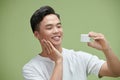 Portrait of young Asian man with cosmetics bottle Royalty Free Stock Photo