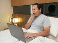 Portrait of young Asian man looked tired sleepy and yawning while looking at laptop, work online business from home Royalty Free Stock Photo