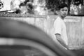 Young Asian man with rusty old car in the streets outdoors