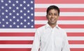 Portrait of young Asian man in shirt smiling against American flag Royalty Free Stock Photo