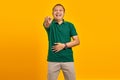 Portrait of young Asian man showing loud laughter with hand on stomach and pointing finger at camera yellow background Royalty Free Stock Photo