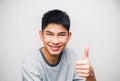 Portrait of a young Asian man smiling with his thumbs up, expressing excellence, or showing successful gestures. In positive human