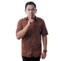 Young Asian Man Wearing Batik Shirt Shows Shushing Gesture