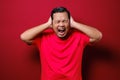 Portrait of young Asian man wearing casual red shirt closing his eyeas and ears dont want or avoiding to hear bad news, stress