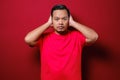 Portrait of young Asian man wearing casual red shirt closing his eyeas and ears dont want or avoiding to hear bad news, stress