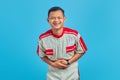 Portrait of young Asian mechanic showing loud laughter with hands on stomach over blue background Royalty Free Stock Photo